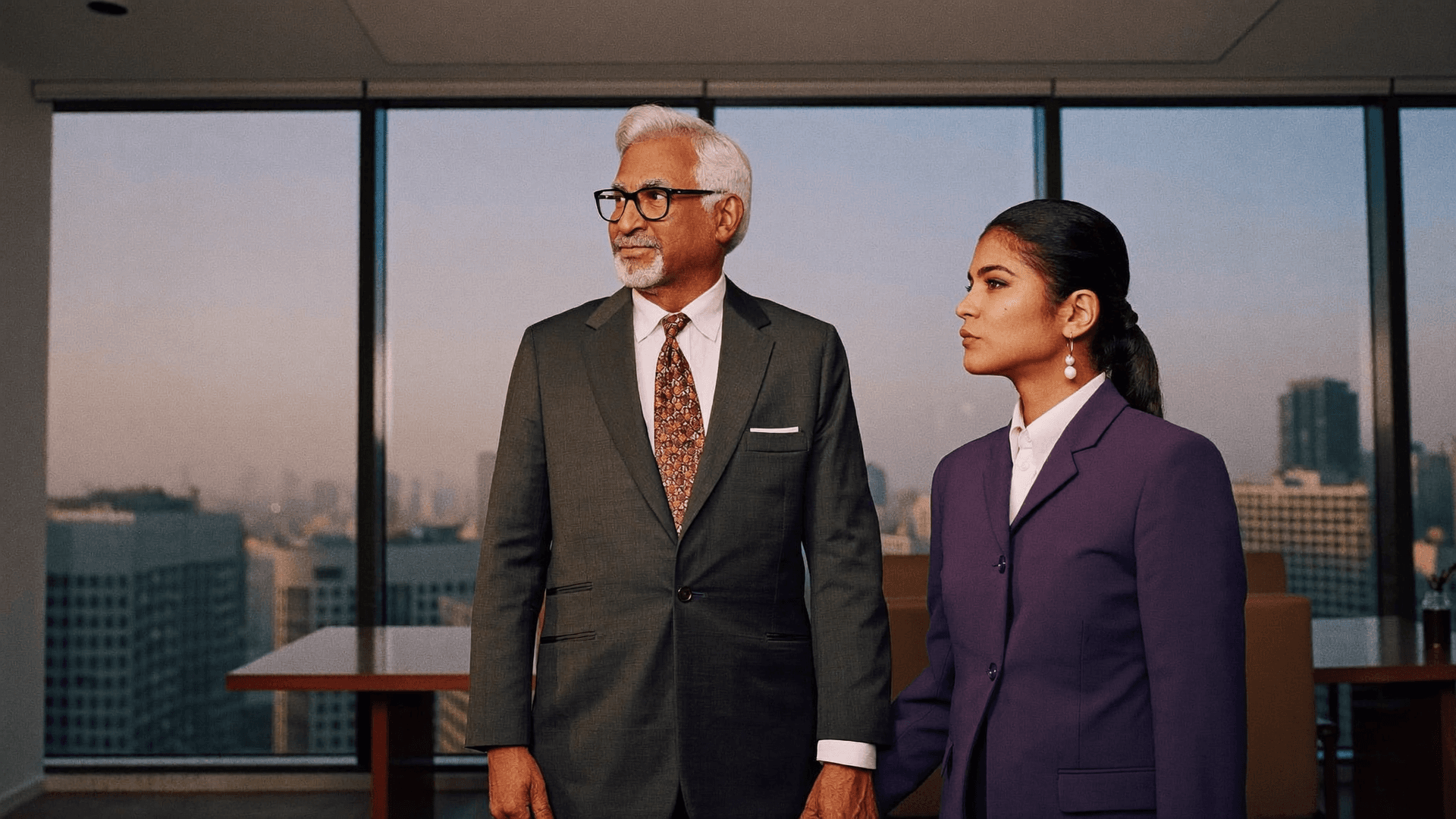 A family-business founder and his successor in a boardroom at dusk, a city skyline beyond