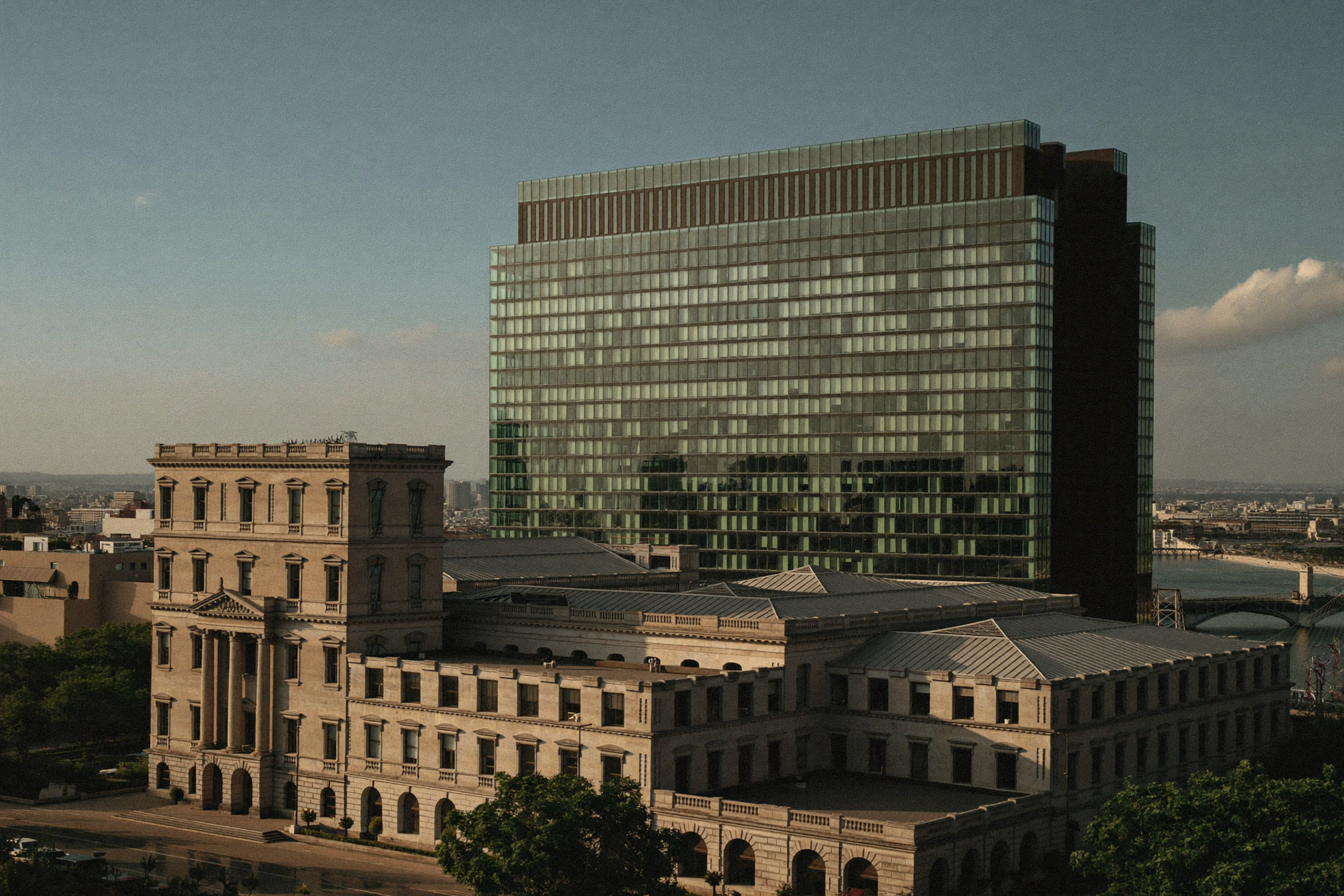 A heritage family-business headquarters beside a modern glass tower in a Gulf city